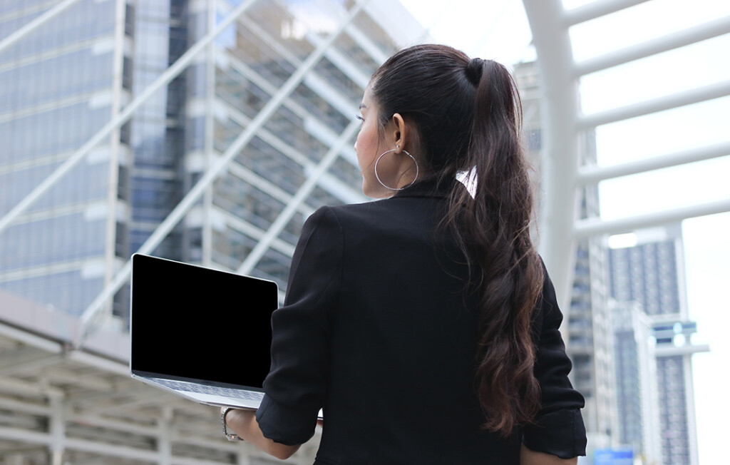 Geschäftsperson mit Tablet in einem modernen Bürogebäude, stellvertretend für die digitale Transformation und mobiles Computing, ermöglicht durch hochleistungsfähige IC-Substrate von AT&S.